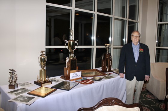 Walt Struzek next to table arrayed with trophies and memorabilia